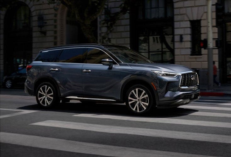 INFINITI QX60 driving on a city street, highlighting its performance and style