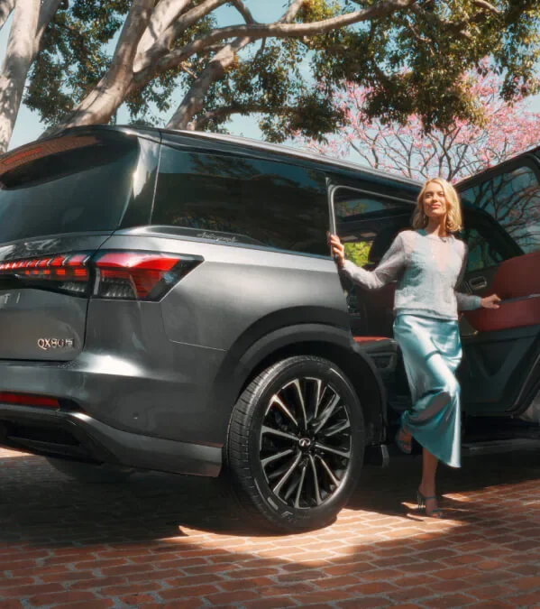 A dealership representative speaking with customers beside an INFINITI vehicle.