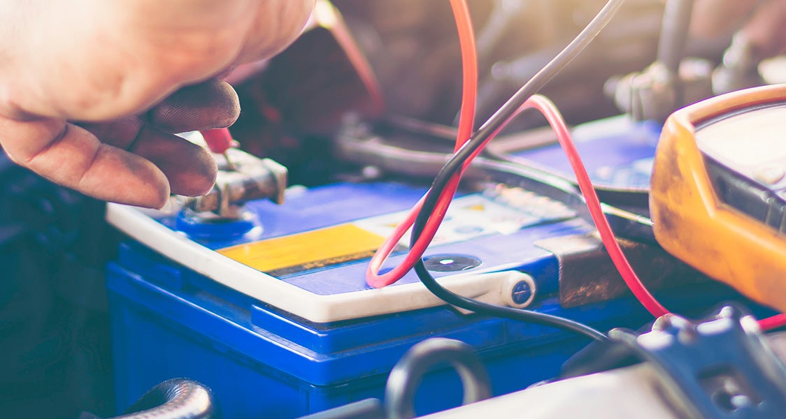 Mechanic testing a car battery with diagnostic tools